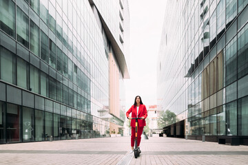 Female professional riding electric push scooter to commute in city