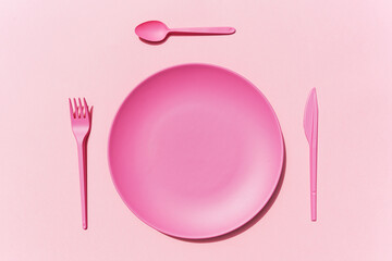 Studio shot of pink plastic plate and cutlery