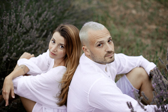 Couple sitting on lavender field looking at camera