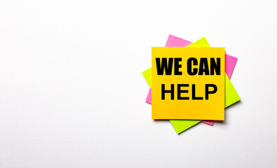On a light background - bright multicolored stickers with the text WE CAN HELP. Copy space