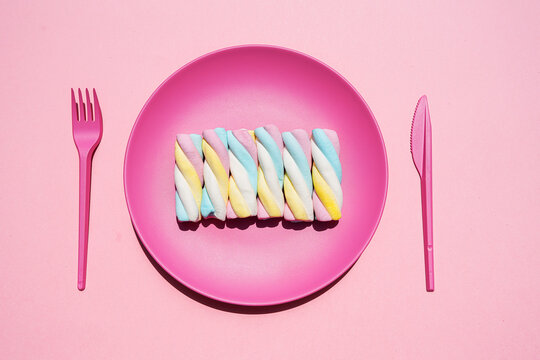 Studio shot of plastic plate with row of twisted marshmallows