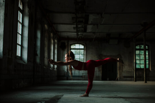 Woman practicing warrior 3 pose at abandoned factory