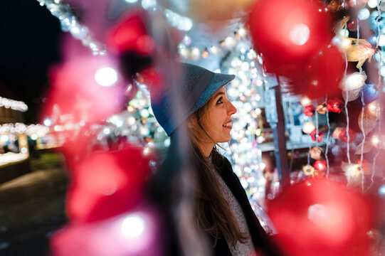 Smiling woman watching a stand on fairground at night