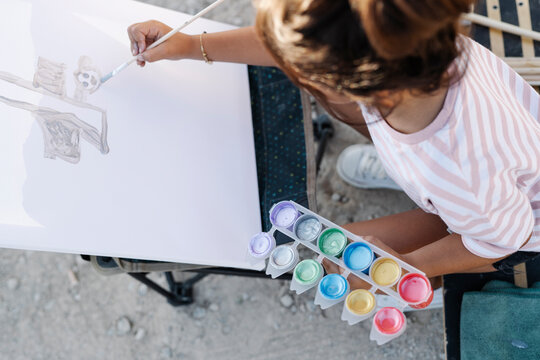 Elementary girl painting at park during sunset