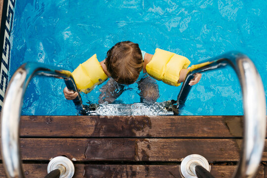 Little girl on ladder of pool