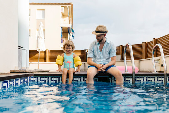 Little girl with her uncle sitting on poolside