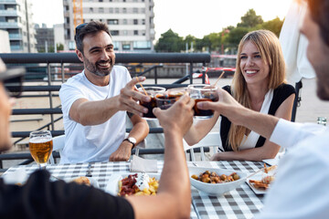 Happy friends toasting Spanish vermouth at sidewalk cafe