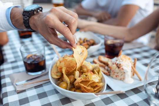 Cropped image of man having potato chip at cafe
