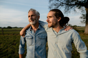 Father and adult son embracing on a meadow in the countryside