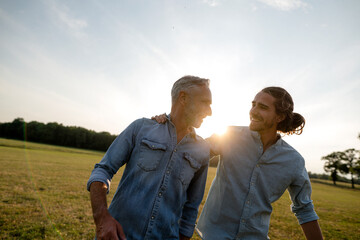 Happy father with adult son on a meadow in the countryside at sunset