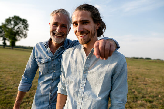 Portrait of happy father with adult son on a meadow in the countryside