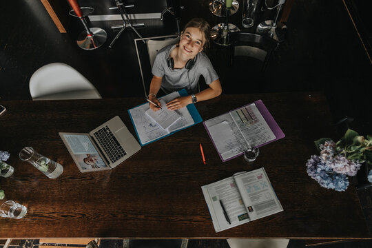 Teenage girl studying from home, using laptop