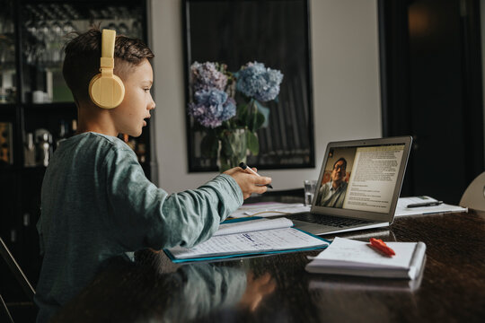 Schoolboy learning at home, using laptop and headphones