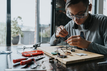 Young man tinkering with soldering iron at home