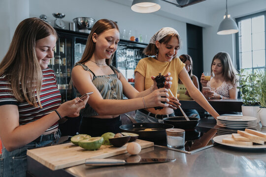 Girlfriends preparing healthy lunch together, frying eggs in kitchen
