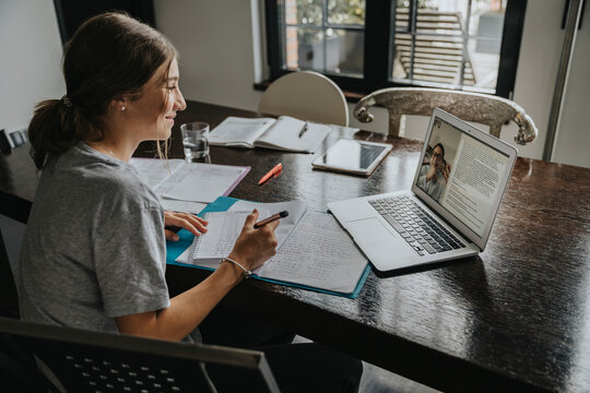 Teenage girl studying from home, using laptop