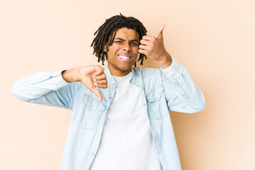 Young african american rasta man showing thumbs up and thumbs down, difficult choose concept