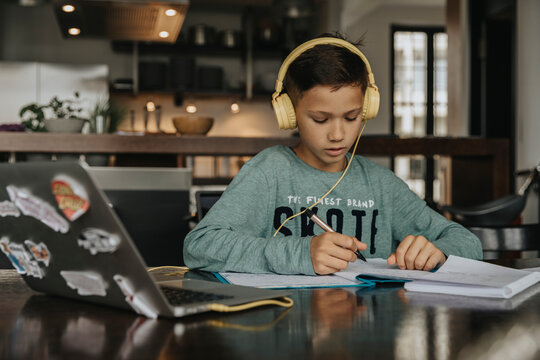 Schoolboy learning at home, using laptop and headphones