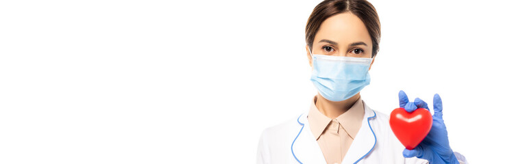 Panoramic shot of doctor in medical mask in latex glove holding heart isolated on white