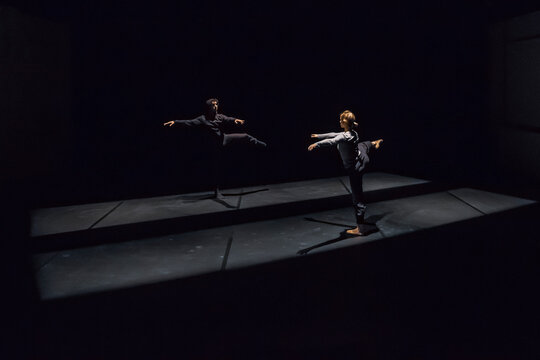 Male and female dancer performing comtemporary ballet on black stage