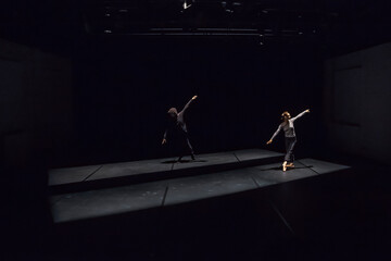 Male and female dancer performing comtemporary ballet on black stage
