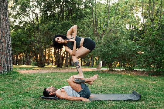 Man balancing girlfriend on legs while practicing acroyoga in public park
