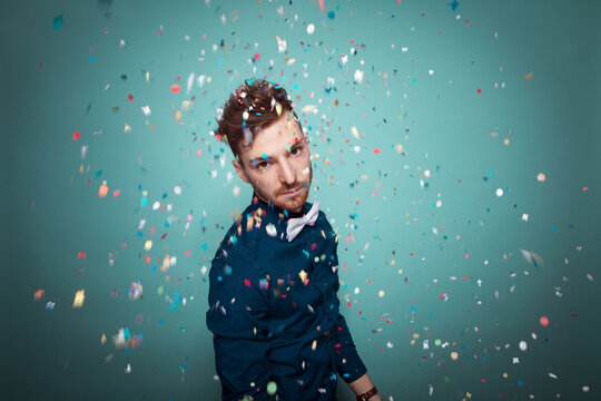 Portrait of young serious man throwing confetti