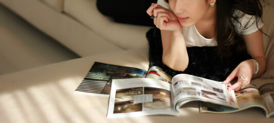 woman reading magazine on sofa in evening