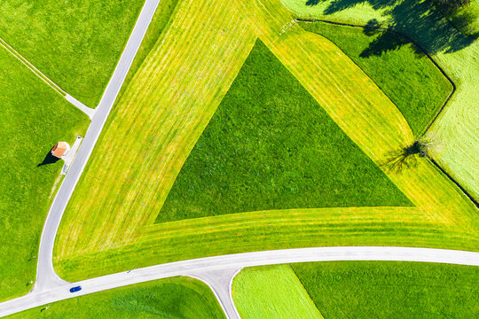 Germany, Bavaria, Hopferau, Drone view of Kapelle Saint Antonius and triangle shaped field in spring