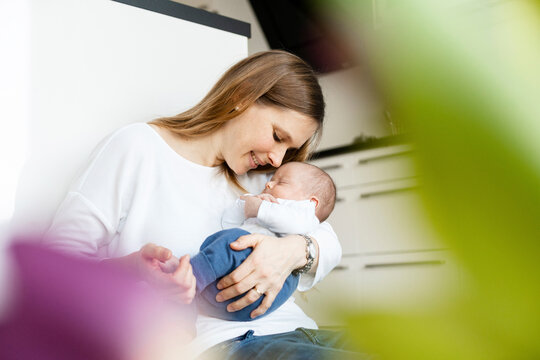 Mother holding sleeping baby boy in arms at home