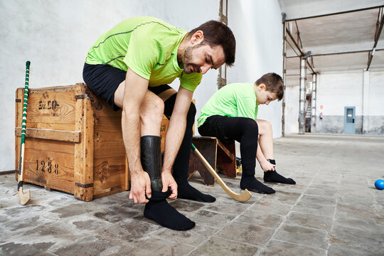 Mature man and son wearing socks while sitting on wooden box at court