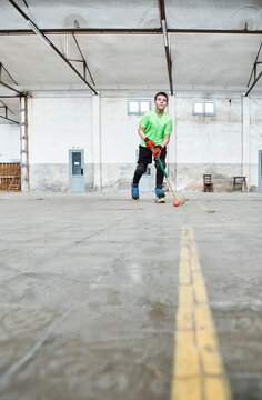 Surface level view of boy practicing roller hockey at court