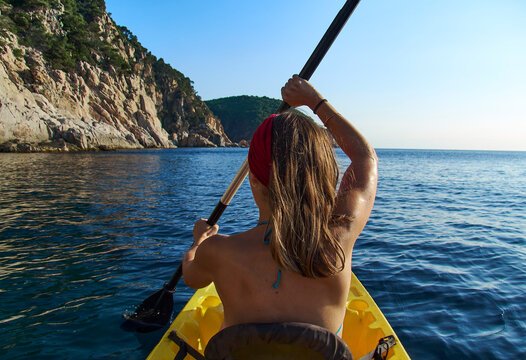 Woman kayaking while sitting in boat against clear sky