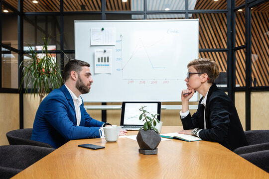 Confident businesswoman listening while looking at executive during job interview in board room
