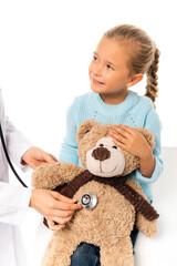 Smiling child holding soft toy near doctor with stethoscope isolated on white