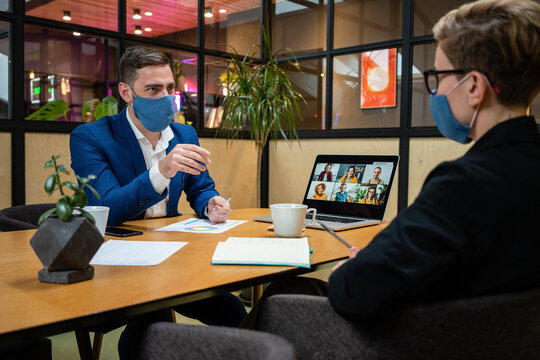 Male and female entrepreneurs wearing masks while planning strategy in board room during pandemic