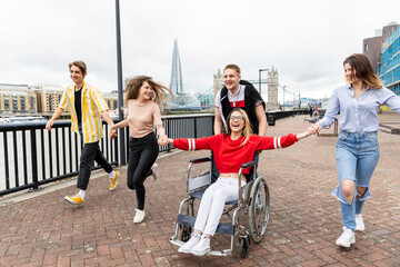 Cheerful men and women with disabled female friend enjoying in city, London, UK
