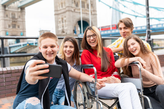 Happy young male and female friends taking selfie with Tower Bridge in background, London, UK