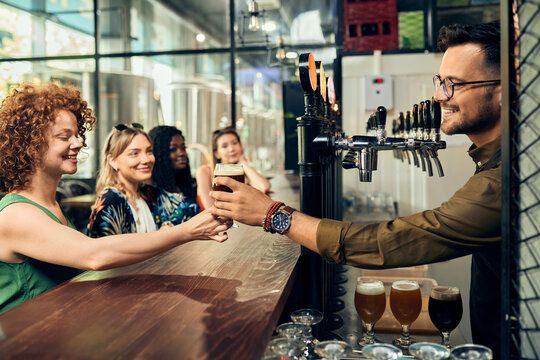 Barkeeper handing over glass of beer to woman in a pub
