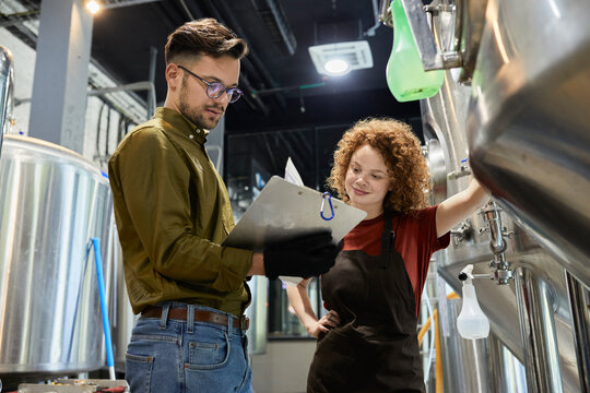 Man and woman working in craft brewery checking document