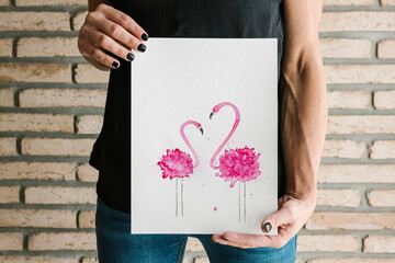 Close-up of woman hand showing painted image while standing against brick wall at home