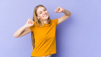 Young blonde woman isolated on purple background celebrating a special day, jumps and raise arms with energy.