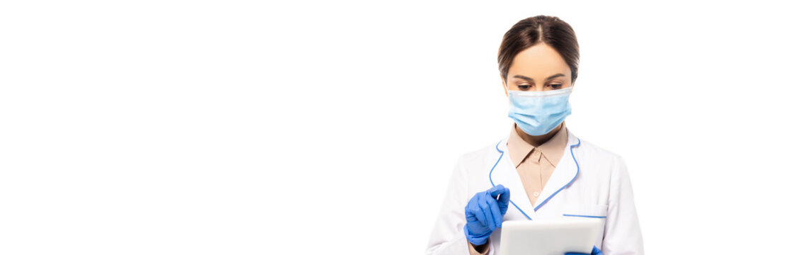Horizontal image of doctor in medical mask and latex gloves using digital tablet isolated on white