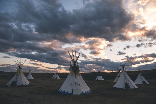 Teepees on landscape against cloudy sky in Glacier National Park