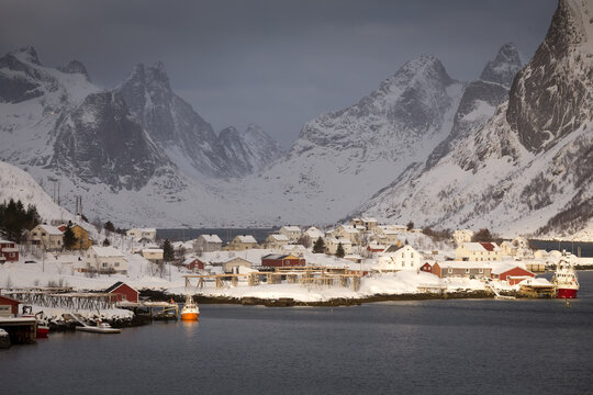 Scenic view of fishing village with mountains in background in winter
