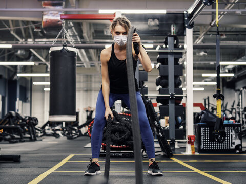 Pandemic gym - woman working out with protective face mask during coronavirus outbreak