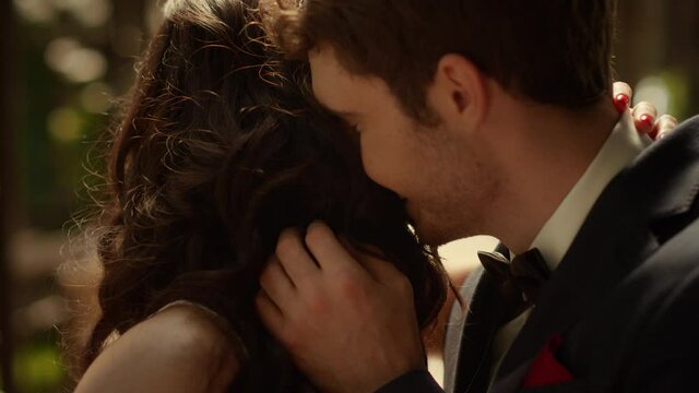 Cheerful couple laughing in garden. Attractive man smelling woman hair outdoors