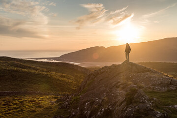 Hiker standing on top of mountain during sunset
