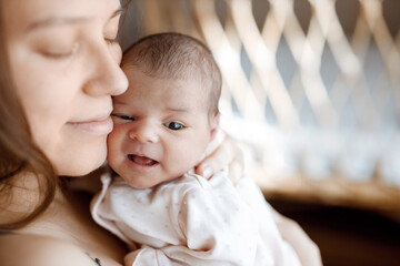 Loving mom carying of her newborn baby at home. Woman holds and hugs her child.