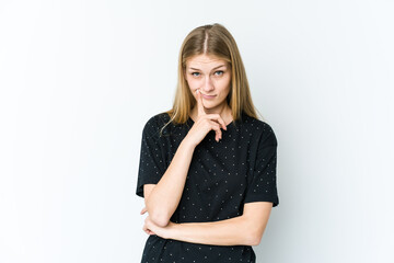 Young blonde woman isolated on white background looking sideways with doubtful and skeptical expression.